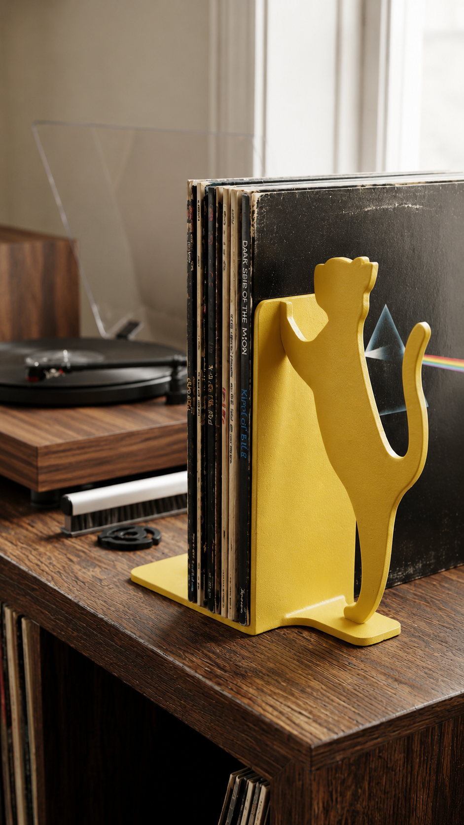 Yellow cat silhouette vinyl record bookend on a wooden shelf.