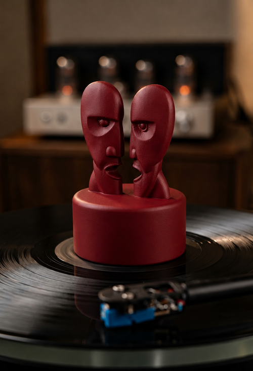 Dark red record stabilizer with dual face sculpture on a turntable.