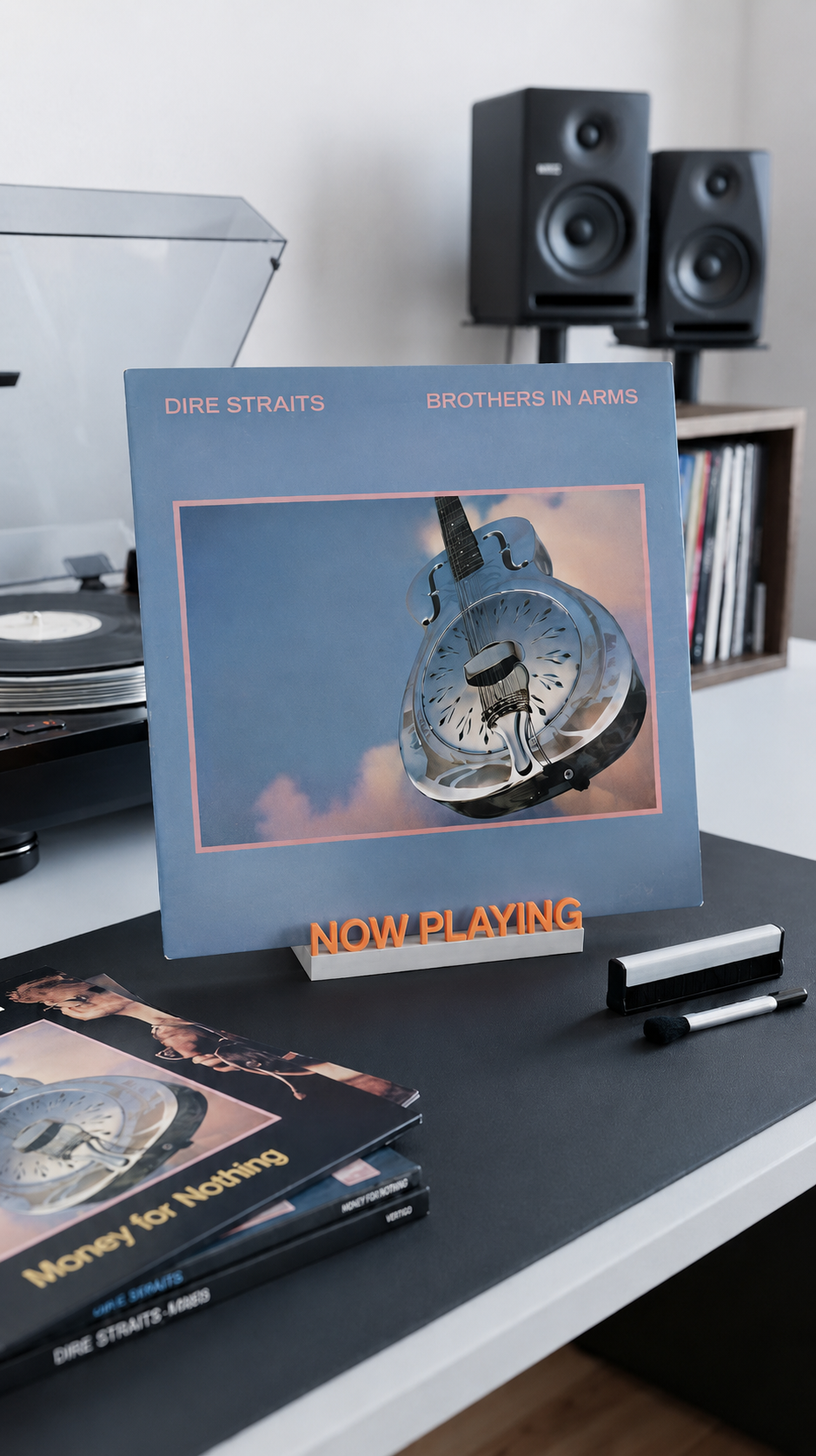 Orange and white 'Now Playing' vinyl record stand holding an album on a desk.