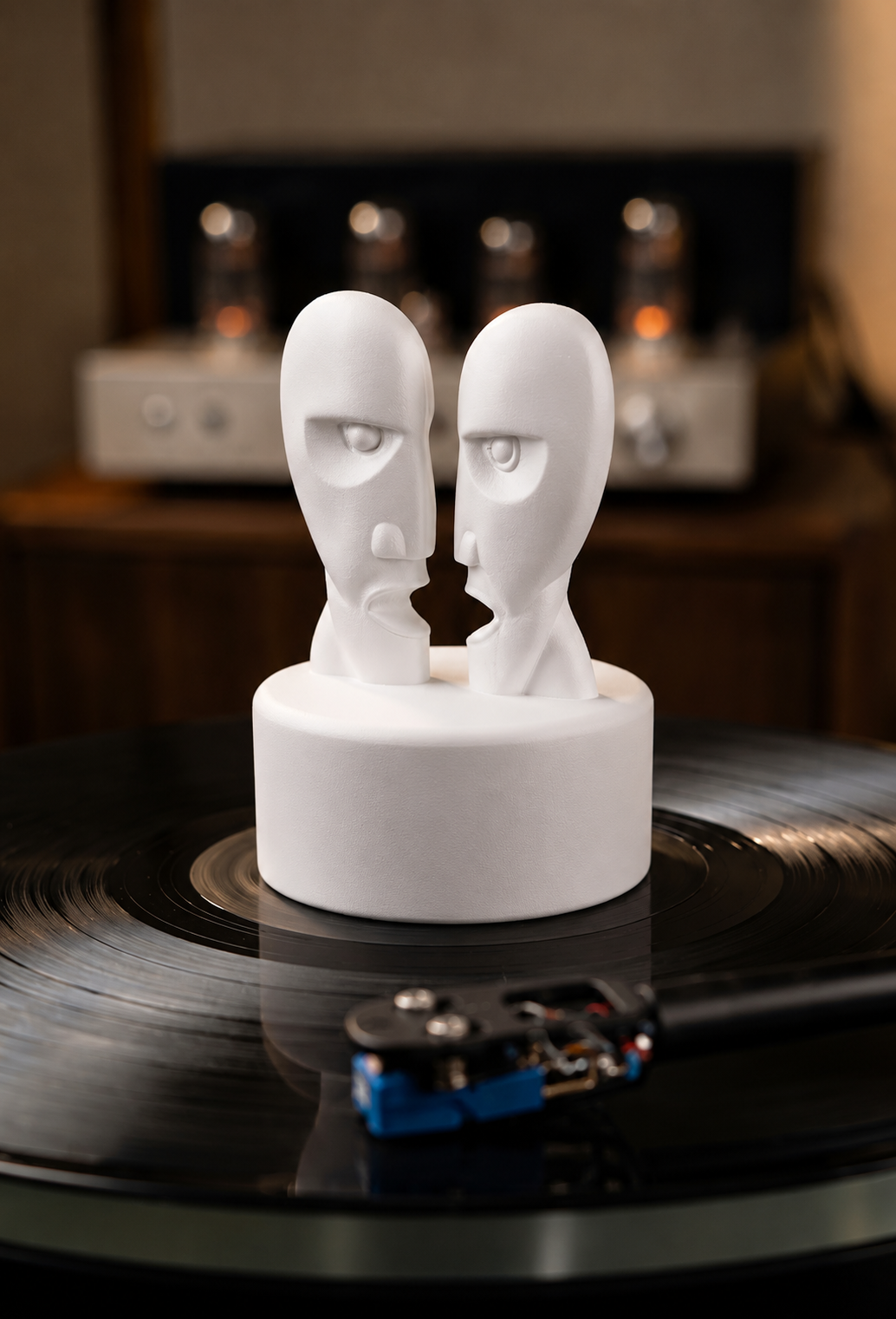 White record weight with dual face sculpture on a turntable.